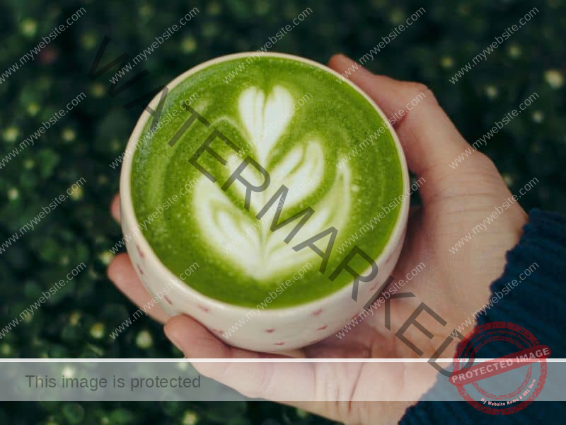 női kéz tart egy matcha lattét